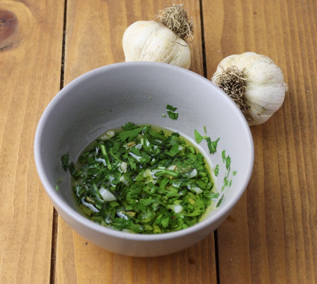 Image showing how to add chopped parsley to the garlic parsley sauce and how to season it with salt and adding lemon juice.